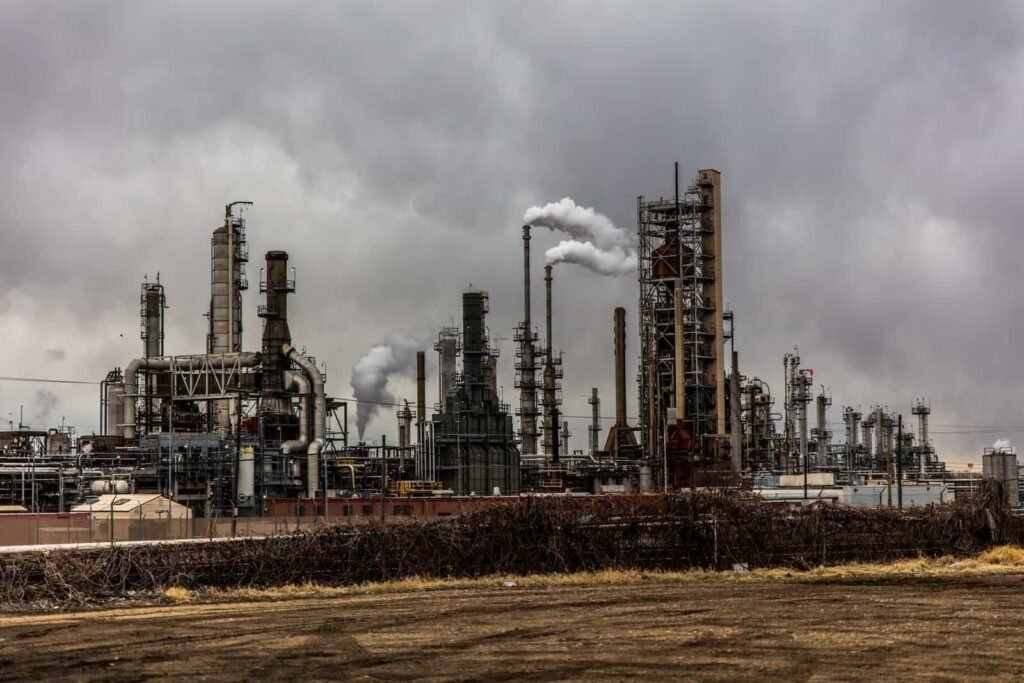 Large industrial factory emitting smoke under cloudy sky, symbolizing air pollution and heavy manufacturing